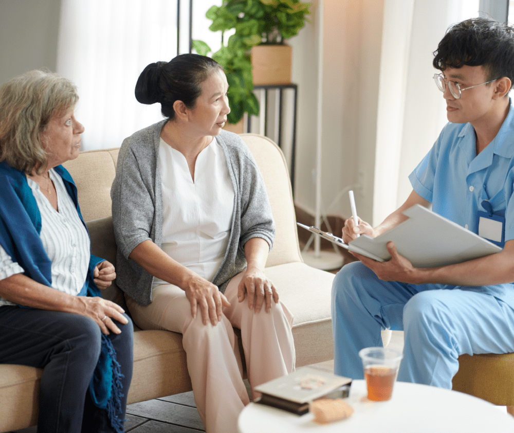 Nursing home doctor talking to senior patients and taking notes in document